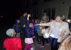 Dzieci stoją wieczorem z nauczycielkami na tarasie przedszkolnym.